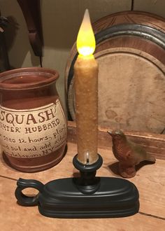 a lit candle sitting on top of a wooden table next to a bird figurine