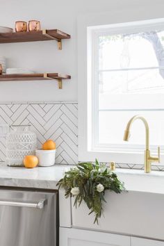 a kitchen with white cabinets and marble counter tops, gold faucet, open shelving above the sink