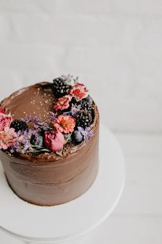 a chocolate cake with flowers and berries on top