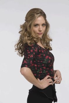 a woman posing with her hands on her hips and wearing a black dress, red flowered top