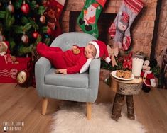 a baby is laying on a chair in front of a christmas tree