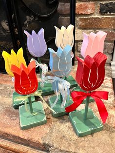 three colorful vases with bows are sitting on a table next to a fire place