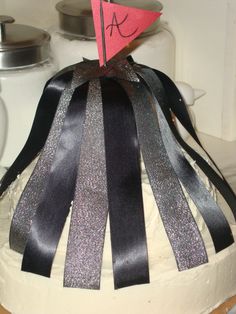 a cake decorated with black and silver ribbons