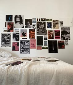 a white bed topped with lots of posters on the wall