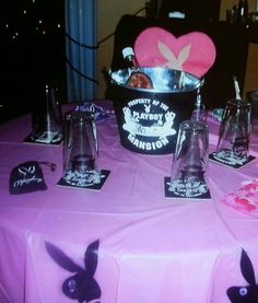 a pink table topped with lots of bottles and cups filled with liquid next to bunny ears