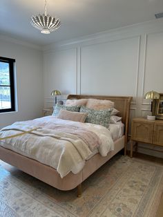 a bedroom with a bed, dresser and window in the corner that has a chandelier hanging above it