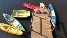 several canoes are tied to a dock with people laying on the water in them