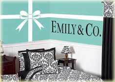 a bed room with a neatly made bed and wall decals on the walls that say,'family & co '