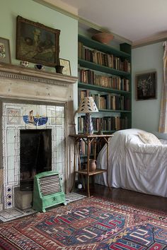 a bedroom with a bed, fireplace and bookshelf filled with lots of books