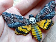 a hand holding a small yellow and black butterfly