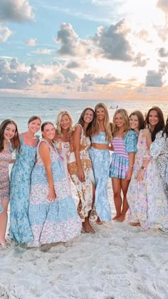 a group of women standing next to each other on top of a white sandy beach