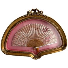 an ornately decorated pink and gold fan on a white background with clippings