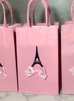 three pink bags with bows and the eiffel tower on them are sitting on a table