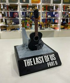 the last of us part ii guitar statue is on display in front of bookshelves