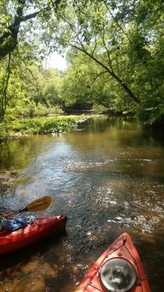 two kayaks are sitting on the bank of a river in front of some trees