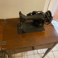 an old sewing machine sitting on top of a wooden table next to a tile floor