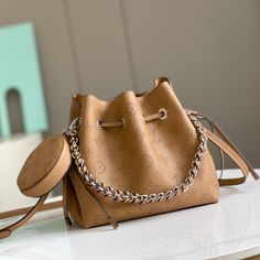 This Bella bucket bag with coin purse is made of Mahina calfskin with a plain weave and Monogram floral pattern surrounded by more than 60,000 custom perforations. Tonal leather trim and hardware complete the overall design. Finished with braided handles and an adjustable, detachable leather shoulder strap.

Dimensions: 19 x 22 x 14 cm Lv Crossbody Bag, Louis Vuitton Yayoi Kusama, Louis Vuitton Capucines, Product Catalogue, Large Cosmetic Bag, Lv Purse, Lv Shoes, Fendi Peekaboo, Medium Handbags