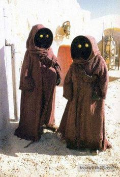 two people dressed in costumes standing next to each other with yellow eyes on their faces