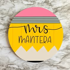 a round magnet with the words mrs mantera written in black ink on it