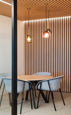 a dining room table and chairs with wooden slats on the wall