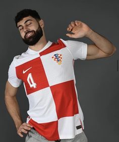 a man with a beard wearing a red and white soccer jersey posing for the camera