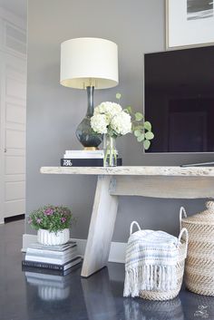 a living room with a tv, vases and flowers on the table in front of it