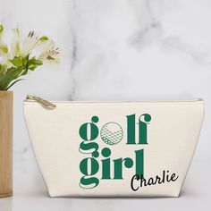 a white bag with the words golf girl on it next to a vase with flowers