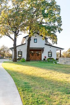 a white house with two trees in front of it and a sidewalk leading up to the door