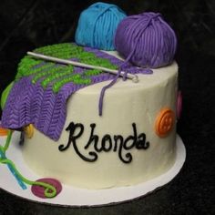 there is a cake that has yarn on it and knitting needles in the top one