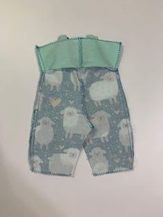 a baby's bib with sheeps on it and green trim around the bottom