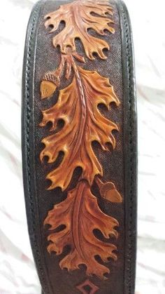 a brown leather belt with an oak leaf design