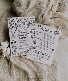 two cards that are sitting on top of a cloth covered surface with flowers and wine glasses