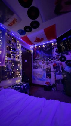 a bedroom with purple lights and decorations on the ceiling, bed in front of it