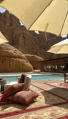 an outdoor area with chairs and umbrellas near a swimming pool in the middle of desert