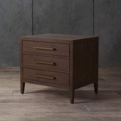 a wooden cabinet with three drawers on the bottom and one drawer in the middle, against a gray wall