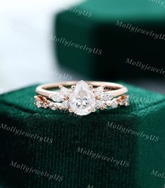 an engagement ring with three diamonds on top of a green velvet cushioned box in front of a white background