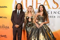 three people standing next to each other on a red carpet