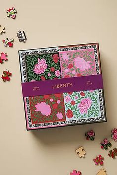 the liberty puzzle box is filled with pink and green floral designs, which are scattered around it