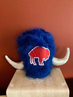 a blue stuffed animal sitting on top of a wooden table next to a red wall