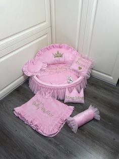 a baby's pink princess bed with matching pillows and diaper on the floor