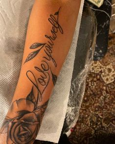 a woman's arm with a rose and the word love is written in cursive writing