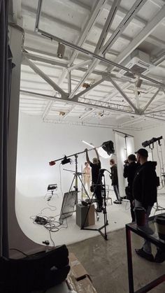 a group of people in a room with cameras and lighting equipment on the floor,