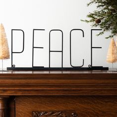 the word peace is placed on top of a mantle with three small trees in front of it