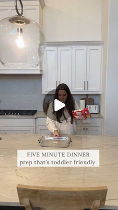 a woman standing in front of a kitchen counter with a pizza box on top of it