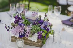 a wooden box filled with lots of purple and white flowers on top of a table