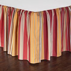 a bed with a red and yellow striped bedskirt