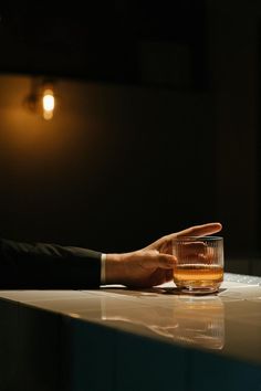 a man in a suit is holding his hand out to a glass on a table