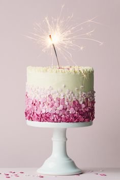 a cake with pink and white frosting has a sparkler sticking out of it