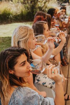 a group of women sitting next to each other holding wine glasses in front of them