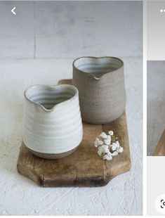 two white vases sitting on top of a wooden tray